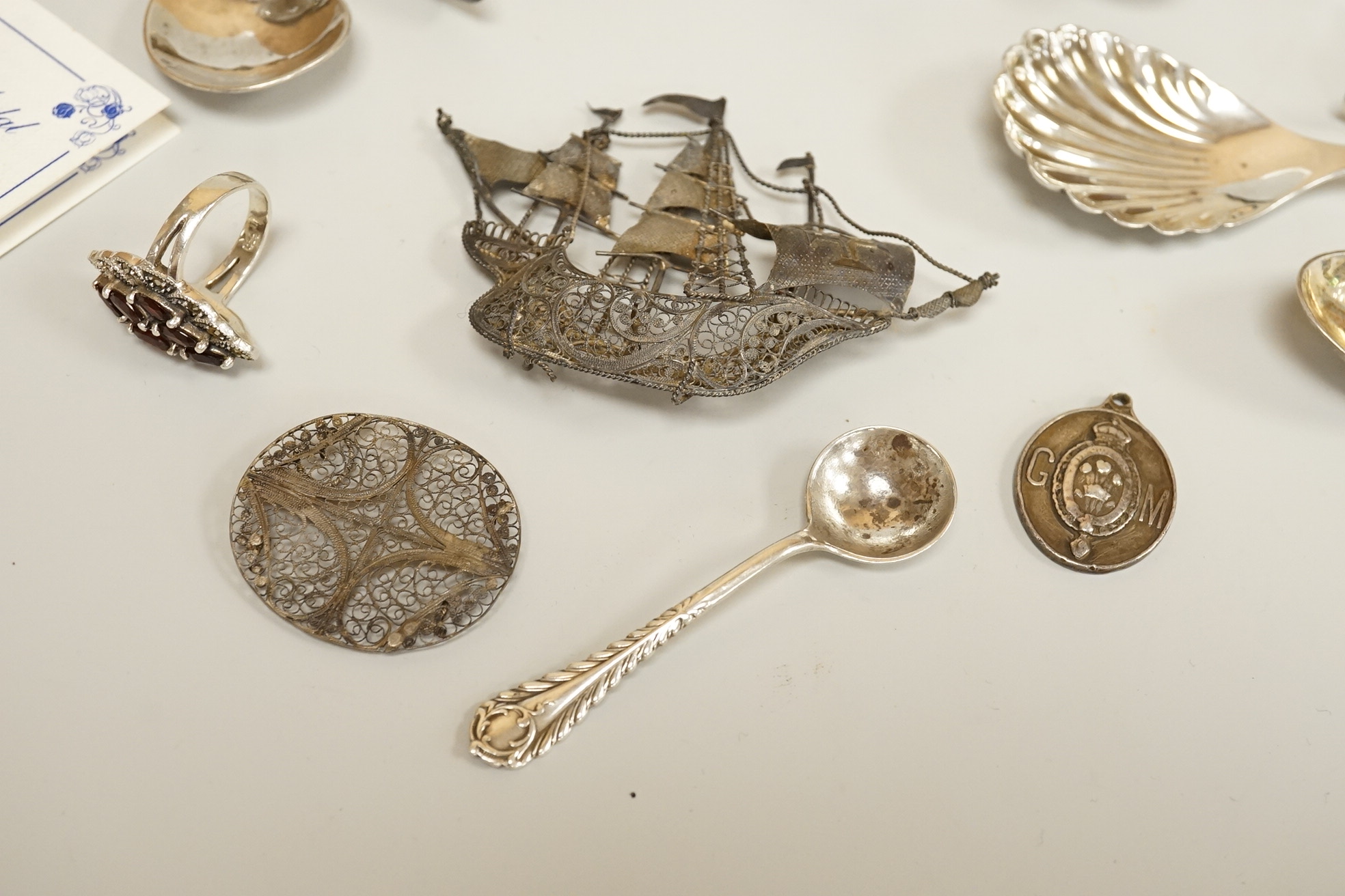 Assorted small silver including a mounted ribbed glass match strike, height 40mm, a small Scottish sterling spoon by Hamish Dawson Bowman, 76mm, a pair of George IV silver sugar tongs, commemorative spoons, an early 20th
